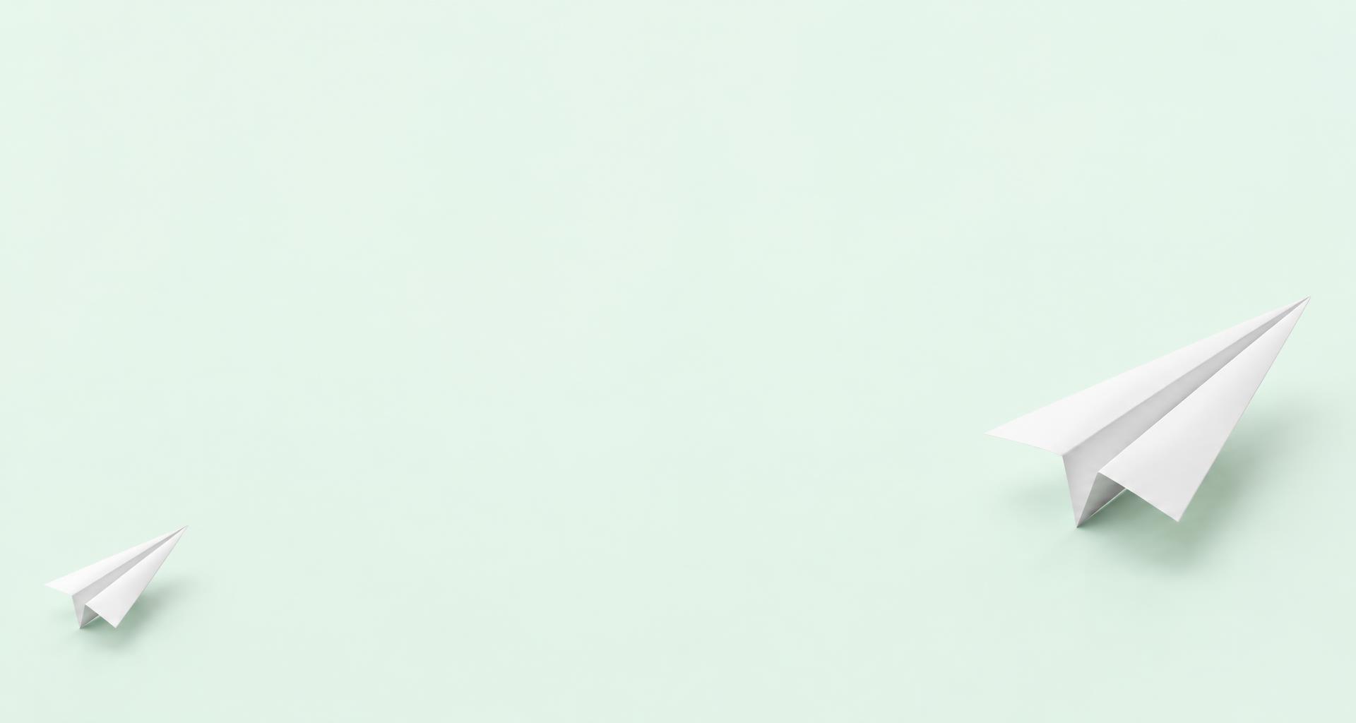 White paper airplanes taking flight on a mint background